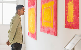 Man looking at paintings hanging on a wall